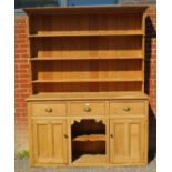 An antique stripped pine ‘dog kennel’ highback kitchen dresser, with plate rack shelving over a