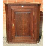 A Georgian oak wall hanging corner cupboard with fielded panelled door and brass lock escutcheon,