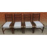 A set of four Edwardian oak dining chairs, with carved and pierced backrests, upholstered in pale