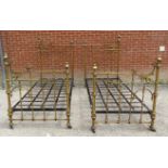 A pair of ornate antique brass single beds with asymmetric scrolled head and footboards featuring