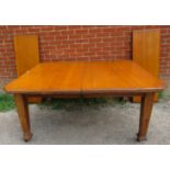 An Arts & Crafts solid light oak wind out extending dining table, with two additional leaves, on