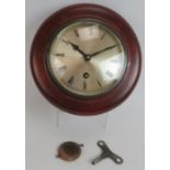 A small turn of the century circular wall clock in mahogany style case. Pendulum and key present.