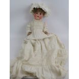 An antique German Armande Marseille doll with triple layered christening gown and cap. Marked