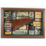 A cased montage of shooting related collectables including a shotgun stock, hip flask, labels,