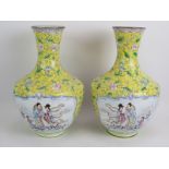 A pair of Chinese Cantonese enamel vases hand decorated with traditional scenes set on a yellow