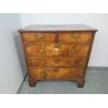 An early 18th century oak and burr walnut chest of two short over three long graduated drawers