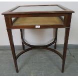 An Edwardian mahogany bijouterie table, the rising lid with inset bevelled glass, on tapering square