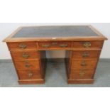 A late Victorian walnut kneehole desk, with inset black rexine writing surface, the pedestals