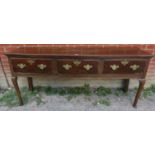 An 18th century oak dresser base of three short drawers, fitted with brass ‘batwing’ handles and