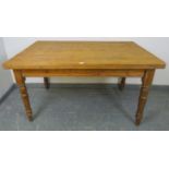 An antique stripped pine scullery table, with long drawer to one end, on turned tapering supports.