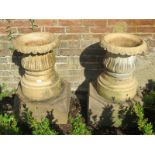 A pair of vintage terracotta garden planters of fluted baluster form, on faceted concrete plinth