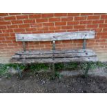 A weathered antique garden bench, the oak slats on iron strapwork supports, bearing remnants of