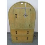 An Art Deco light oak dome topped compactum, the relief carved door opening onto tw