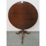 A Georgian oak circular tilt top occasional table, on a tapering turned column with splayed tripod