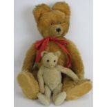 An antique straw filled jointed teddy bear with long snout, hump back and jointed arms, legs and