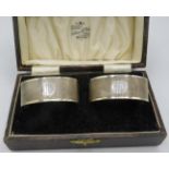 A pair of oval silver napkin rings with engine turned decoration and blank cartonche. Birmingham