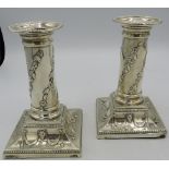 A pair of Victorian silver candlesticks embossed with foliate design on the columns and rams