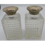 A pair of Victorian square cut glass scent bottles with engraved silver tops, both with inner