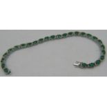 An 18ct white gold oval emerald and diamond line bracelet. Emeralds approx: 8.95 and diamonds