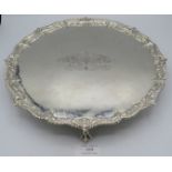 A large Georgian silver salver with engraved and embossed decoration and standing on 3 ball and claw