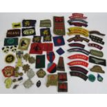 A collection of WW2 British and Canadian military cap badges and cloth badges including Tank