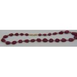 A ruby graduated ovoid flat bead necklace interspaced with yellow metal spacers and 8mm rose