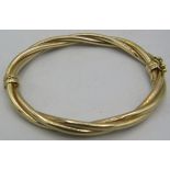 A 9ct yellow gold bangle with three tube twist design and hinged clasp, approx weight 12 grams.