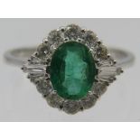 An 18ct white gold oval emerald and diamond cluster ring. Emerald 1.05 ct. Diamonds 0.60ct. (round