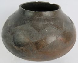 An African tribal pottery bowl of squat form decorated with geometric patterns. Diameter 20cm.