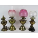 Two brass oil lamps, both with etched Cranberry shades and two similar lamps converted to