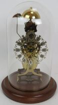 A contemporary brass skeleton clock with German striking movement under a glass dome. No key.