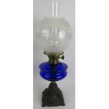 A turn of the century cast iron based oil lamp with Bristol blue reservoir and etched glass shade.