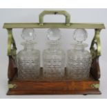 An Edwardian oak 3 decanter tantalus with locking mechanism and nickel mounts. Each decanter hobnail