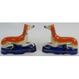 A pair of Staffordshire pottery pen holders in the form of recumbent greyhounds. Height 14cm. Length