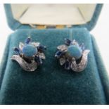 A pair of white metal black opal, sapphire & diamond cluster stud earrings. Each earring with centre