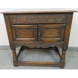 An oak side cabinet in the 17th century taste, with relief carved frieze and twin doors with
