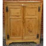 An antique stripped pine pantry cupboard, the doors with fielded panels and cast-iron hinges,