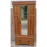 An Edwardian light oak single wardrobe, with bevelled mirror door and fielded front panels, with one