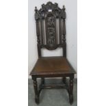 A turn of the century oak hall chair, featuring carved and pierced back rest with heraldic crest