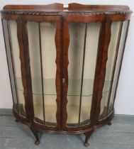 A 1920s mahogany demi-lune glazed display cabinet with gadrooned edge, on cabriole supports.