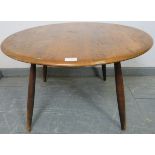 A mid-century elm circular coffee table in the manner of Ercol, on tapering supports. Condition