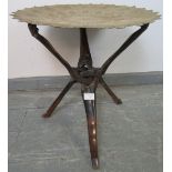 An antique North African tray top table, the shaped and dished brass top intricately hand worked