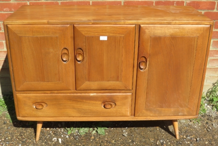 A mid-century elm and beech sideboard by Ercol, housing two cupboards, both with loose shelves,