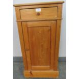 An antique stripped pine bedside cabinet with single drawer and cupboard under with loose shelf,