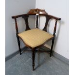 An Edwardian mahogany corner chair, featuring marquetry inlay and pierced back splats, upholstered