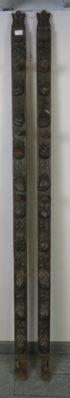 A pair of 19th century oak uprights, each carved with a green man mask and depictions of fruit and