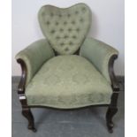 A turn of the century ebonised Ladies armchair with heart shaped backrest and scrolled arms,