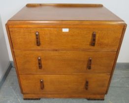 An Art Deco golden oak chest of small proportions, with three long graduated drawers, featuring