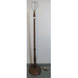 A vintage oak standard lamp with tapering barley twist and baluster turned column on a circular