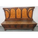 An antique stained pine high-back box settle, ornately carved in the Arts & Crafts taste with
